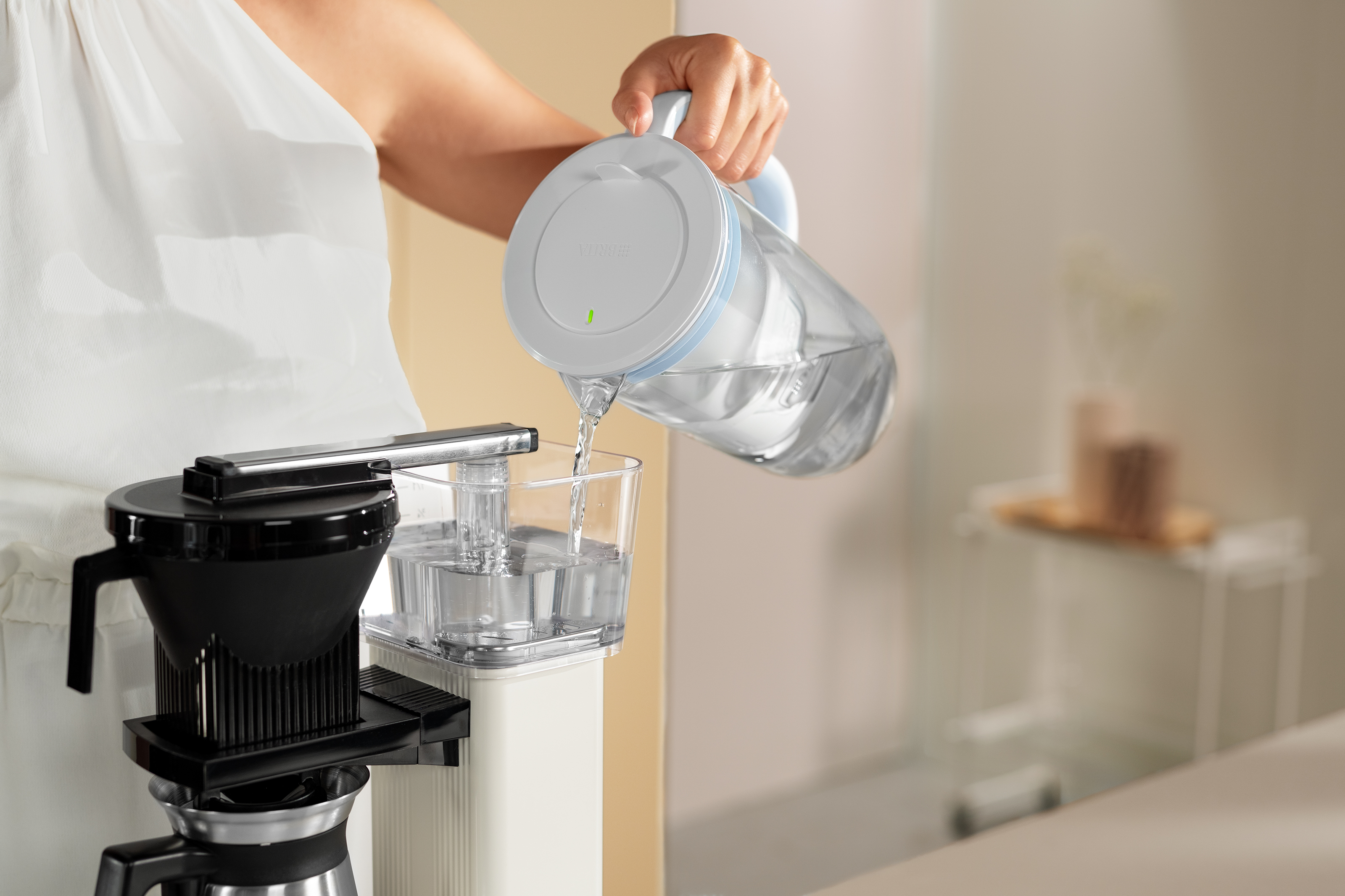 Gefiltertes Wasser wird mit dem Tischwasserfilter BRITA Glas in eine Kaffeemaschine gefüllt