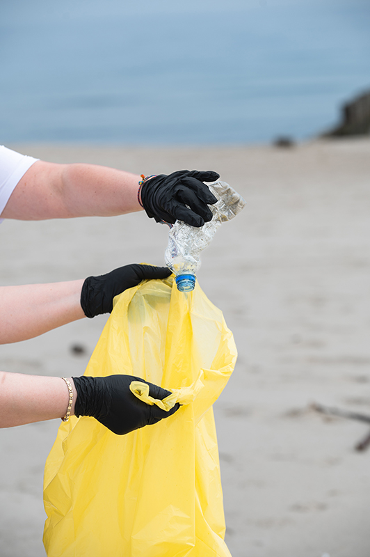 Eine Plastikflasche wird in eine Mülltüte geworfen bei einer Cleanup Aktion in Polen